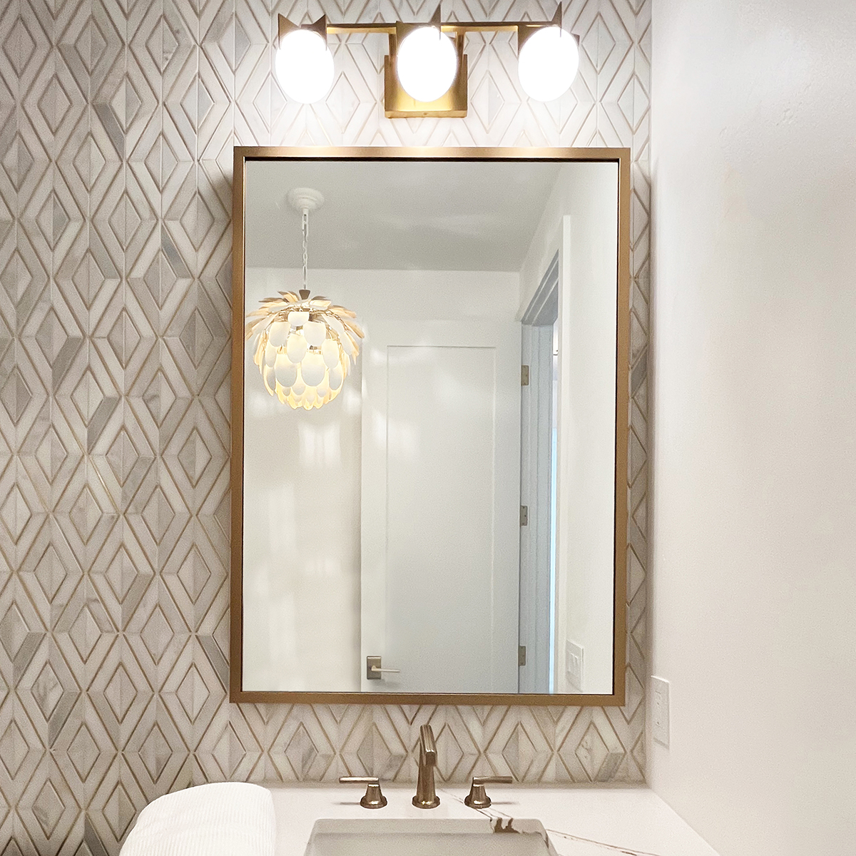 Framed Gold Mirror hanging in bathroom on tiled wall