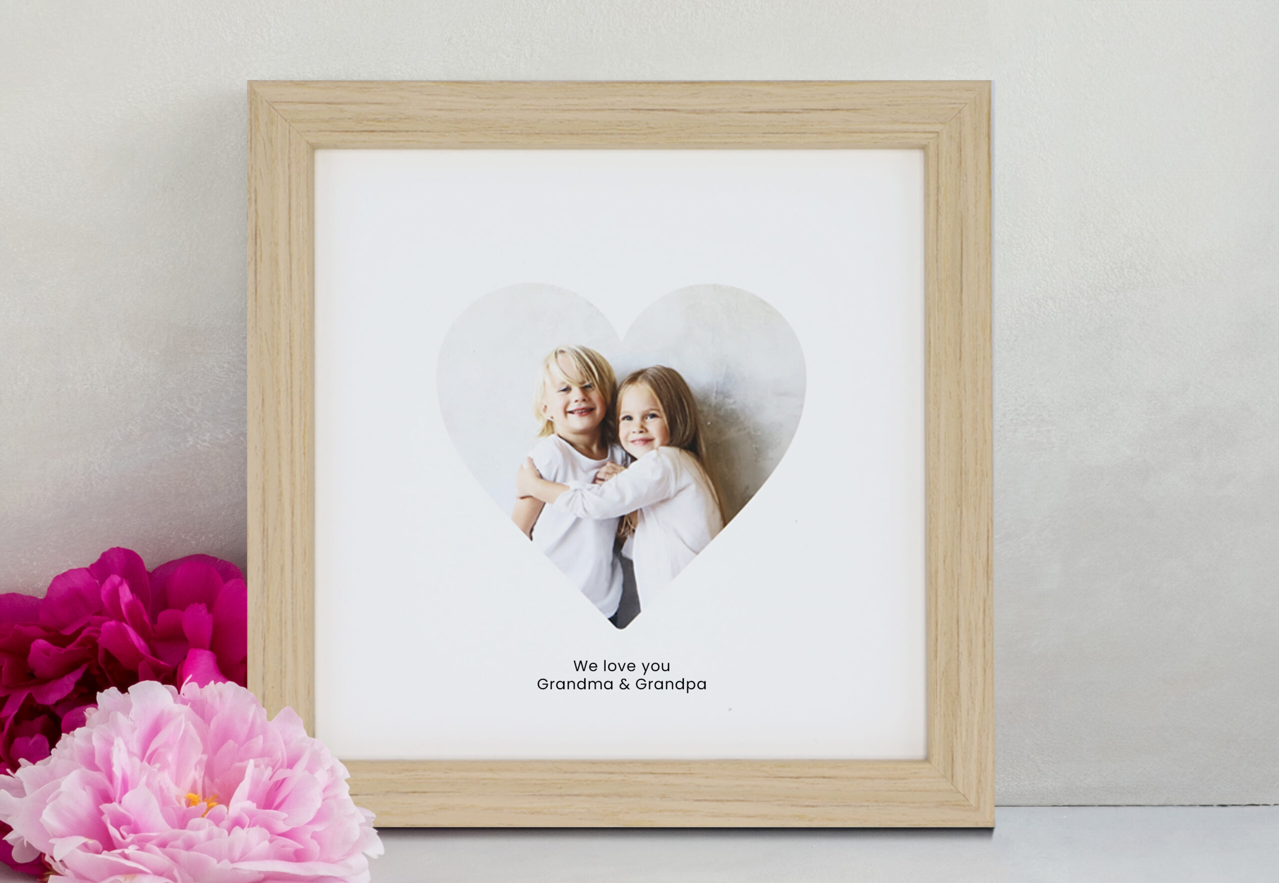 A photo of a Heart image in Pine Wood frame sitting with flowers