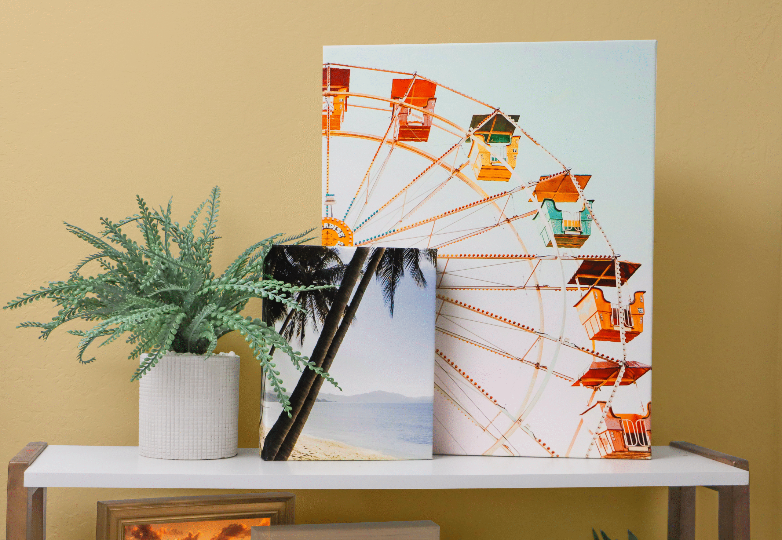 Two canvas prints displayed on a shelf with a plant