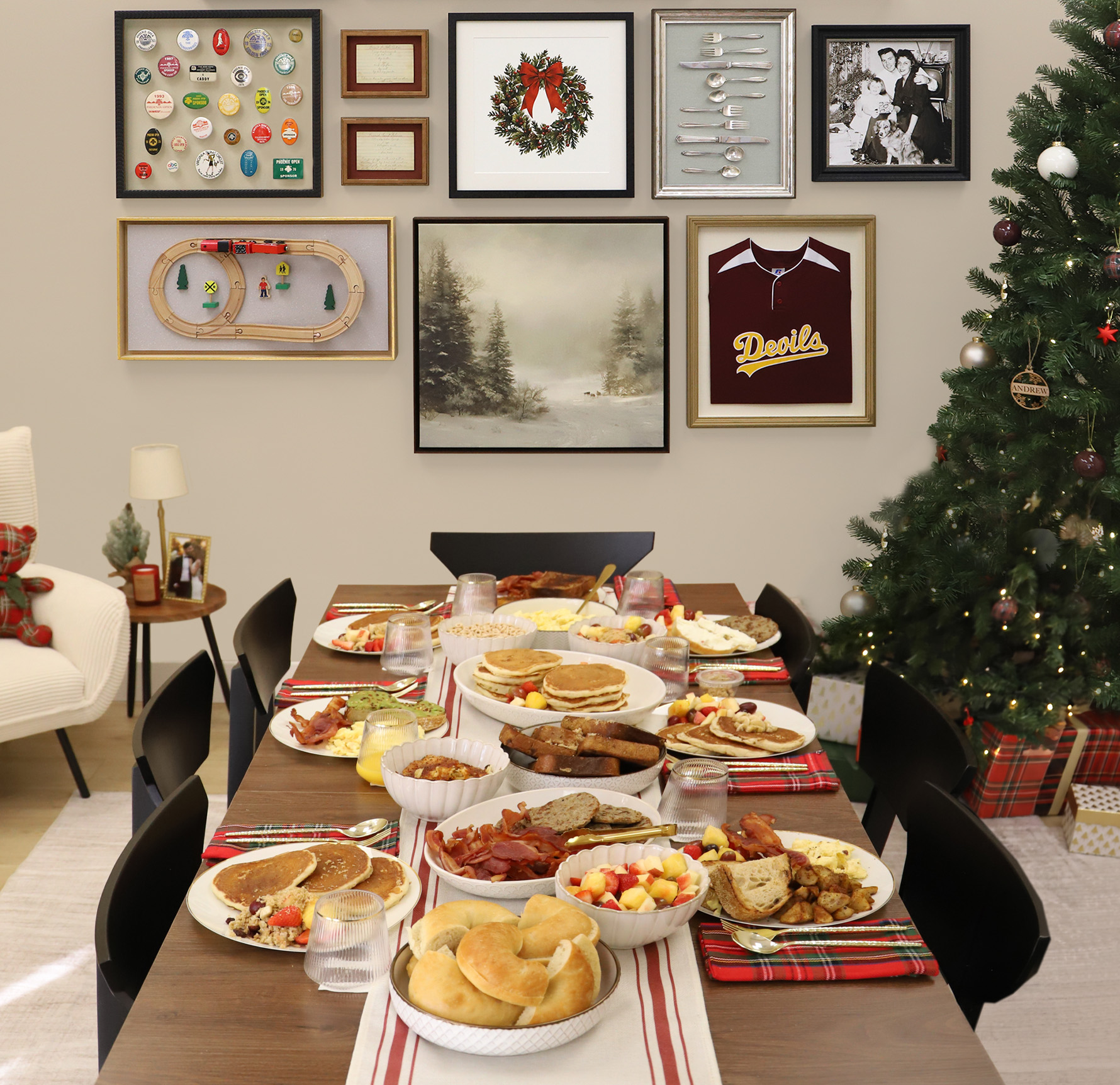 Festive breakfast spread on a dining table next to a Christmas tree, set beneath a custom gallery wall of shadowboxes and framed artwork